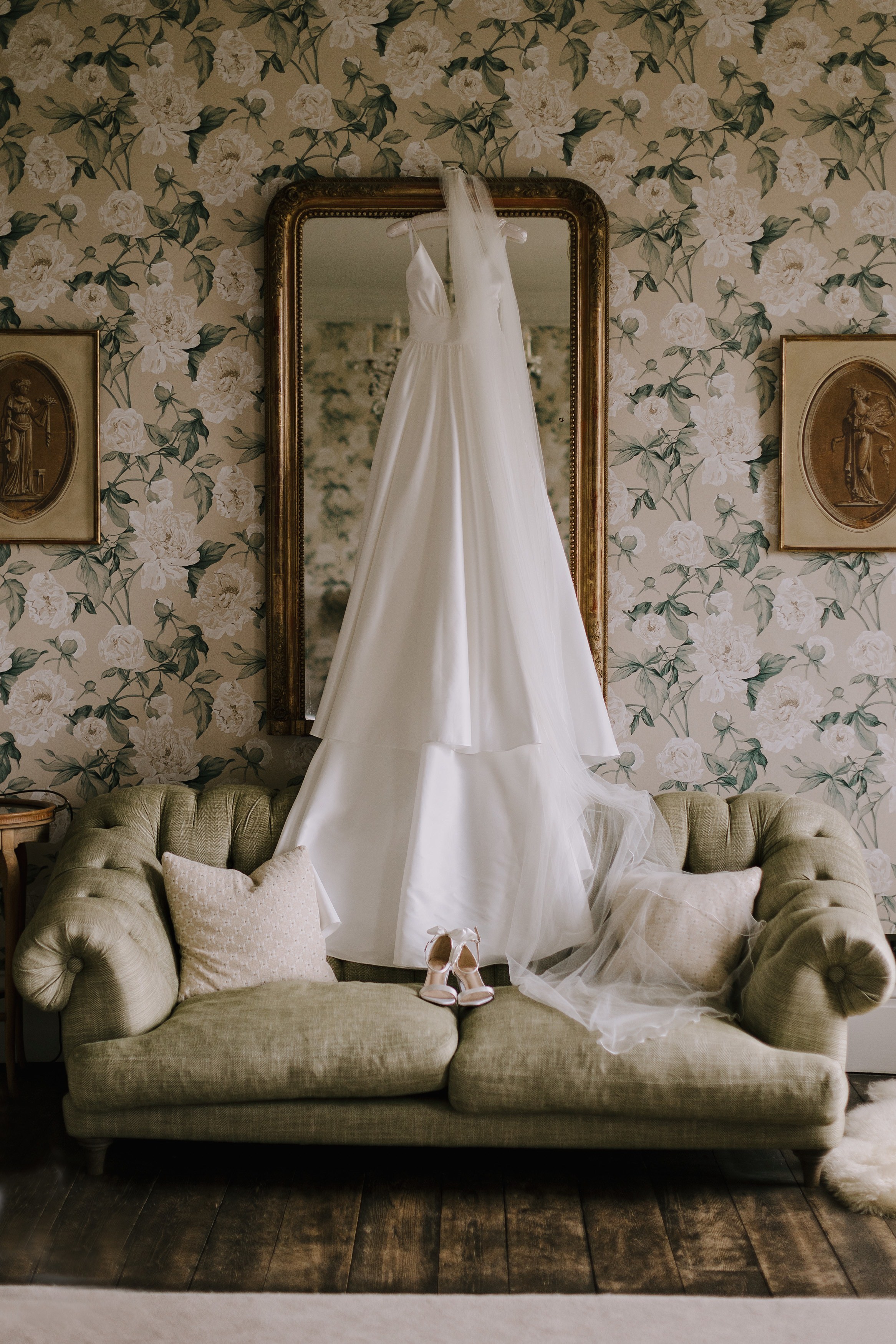 Wedding dress, veil and wedding shoes positioned over a sofa and mirror in a stately home