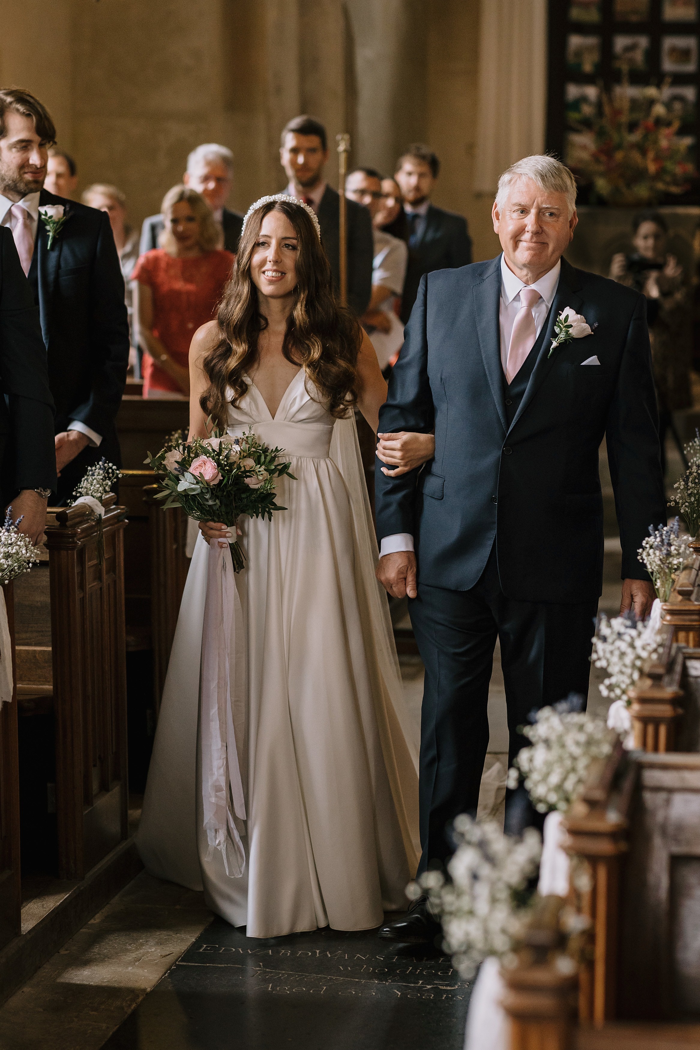A bride walking down the isle holding flowers with the father of the bride
