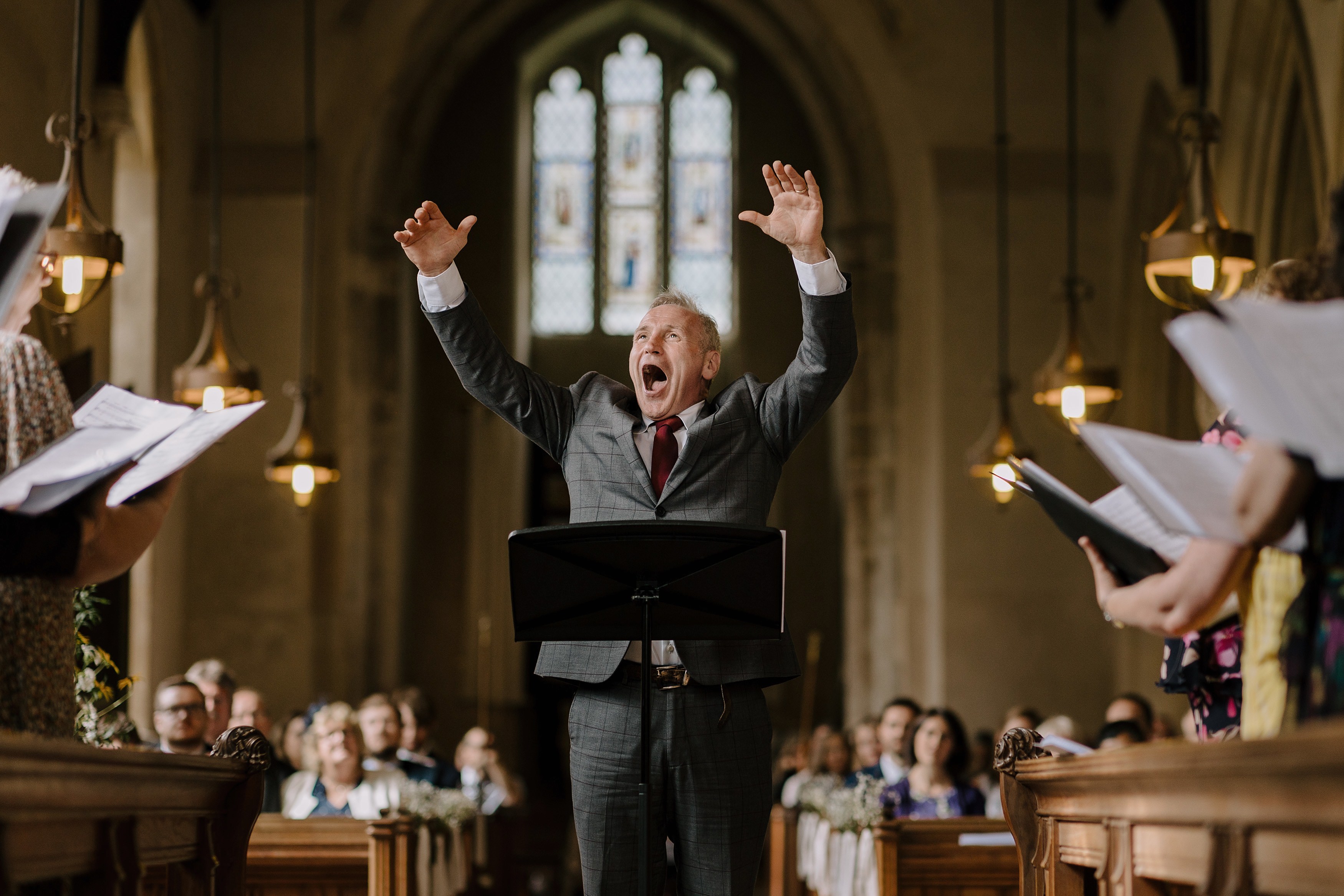 Conductor leading the choir in a hymn during the wedding ceremony