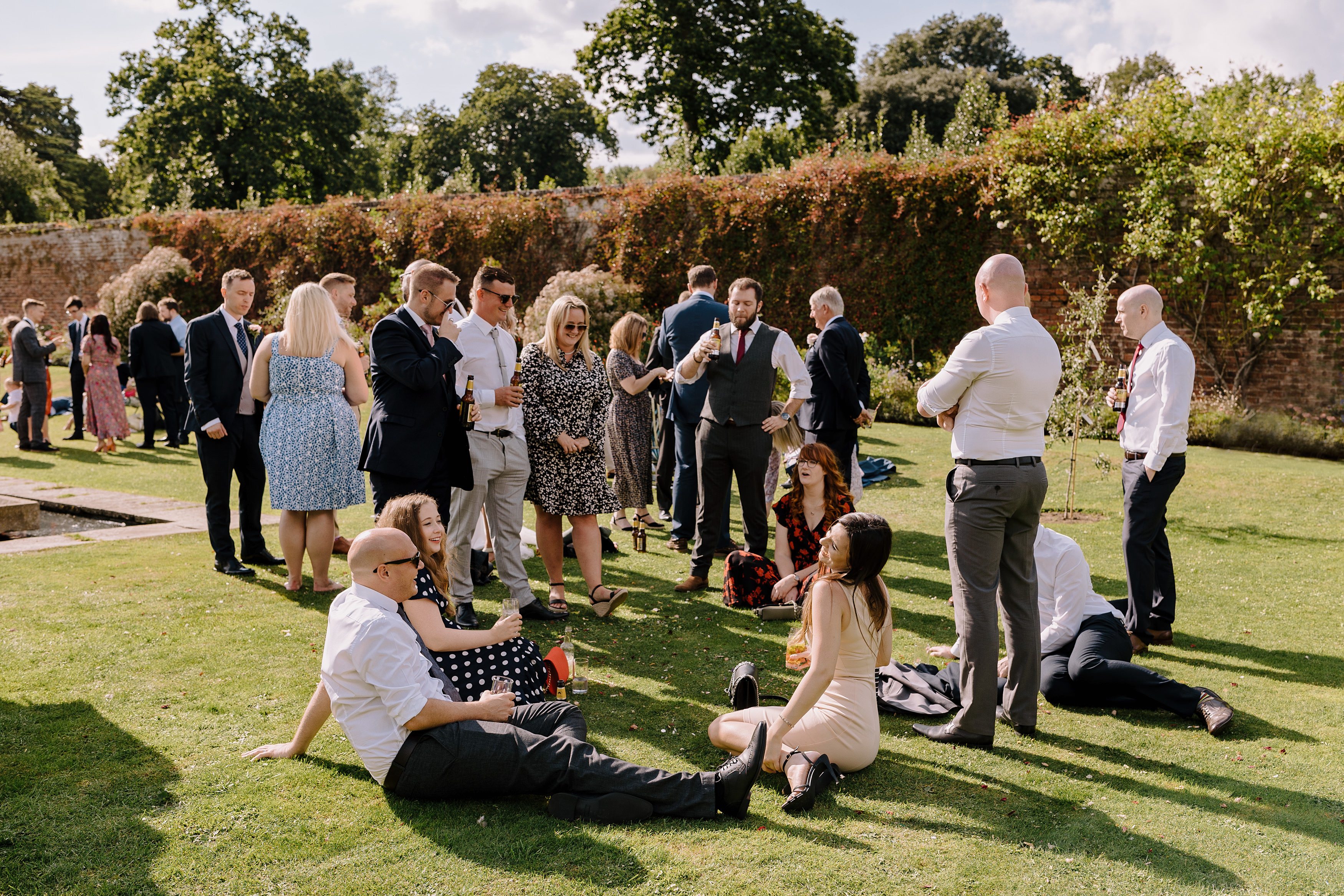 Wedding guests relax by the ornamental pond at Goodnestone Park