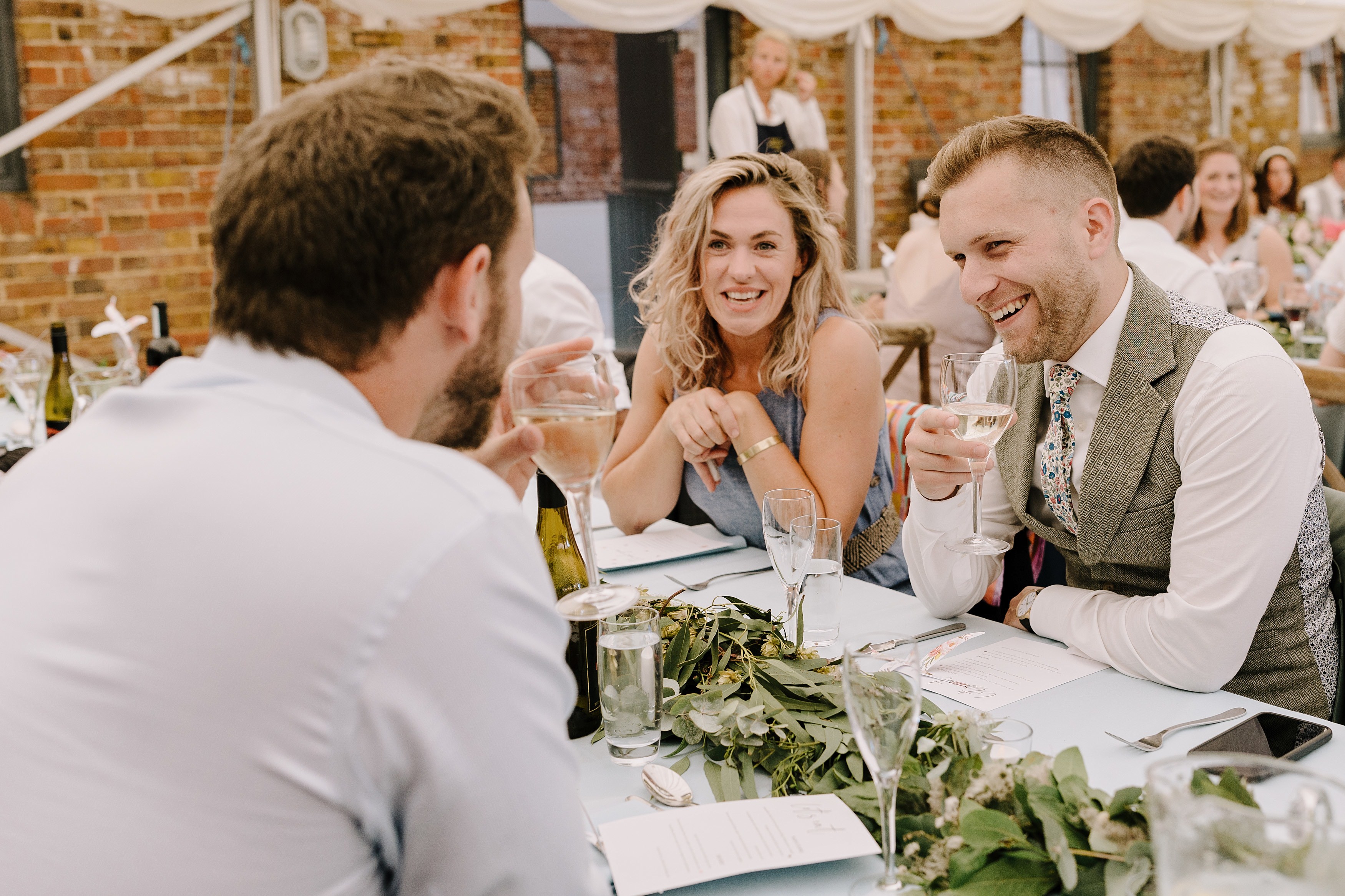 Wedding guests talking and laughing whilst enjoying drinks at their table