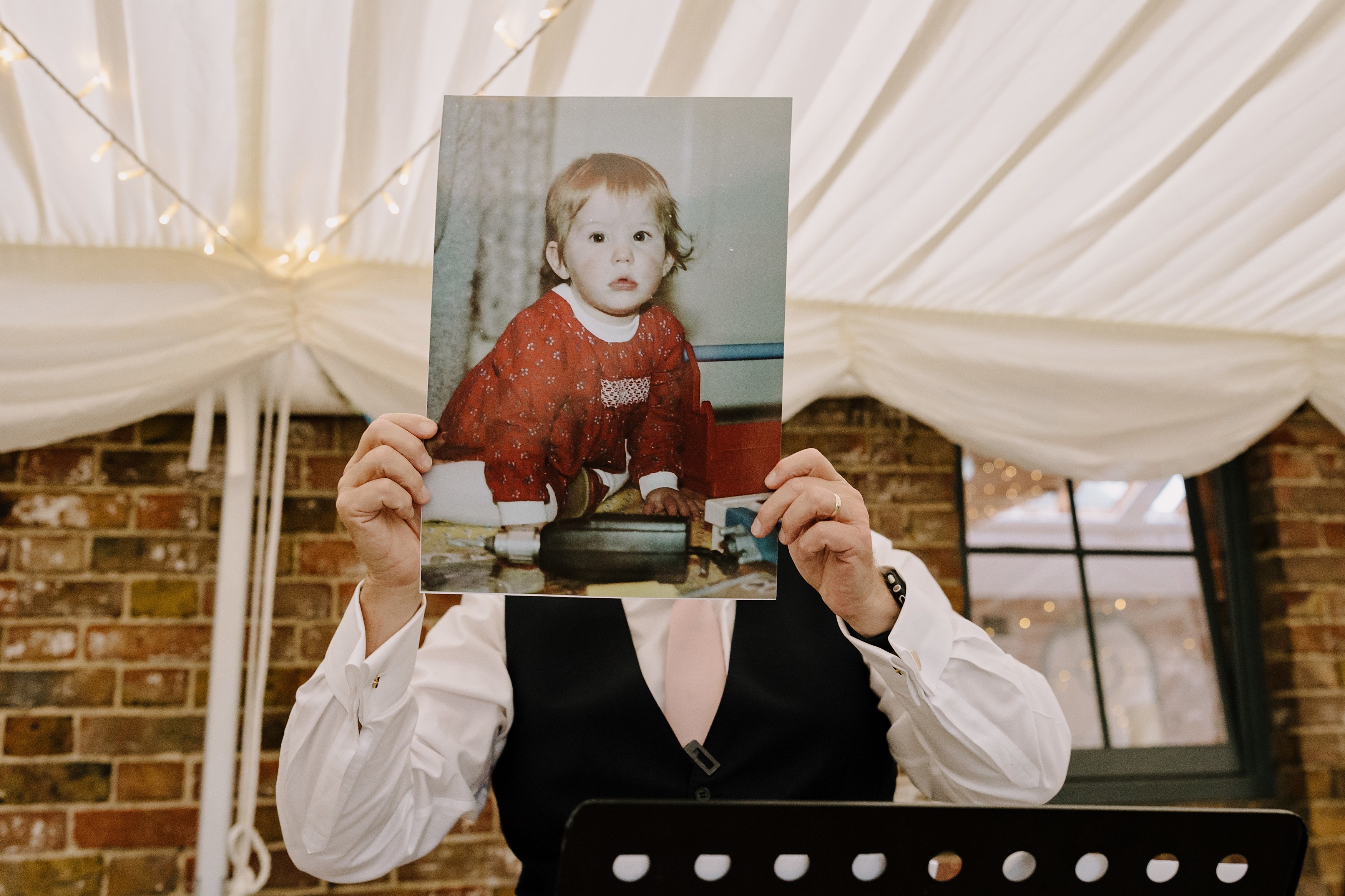 Someone holding up a baby photo of the bride during their speech