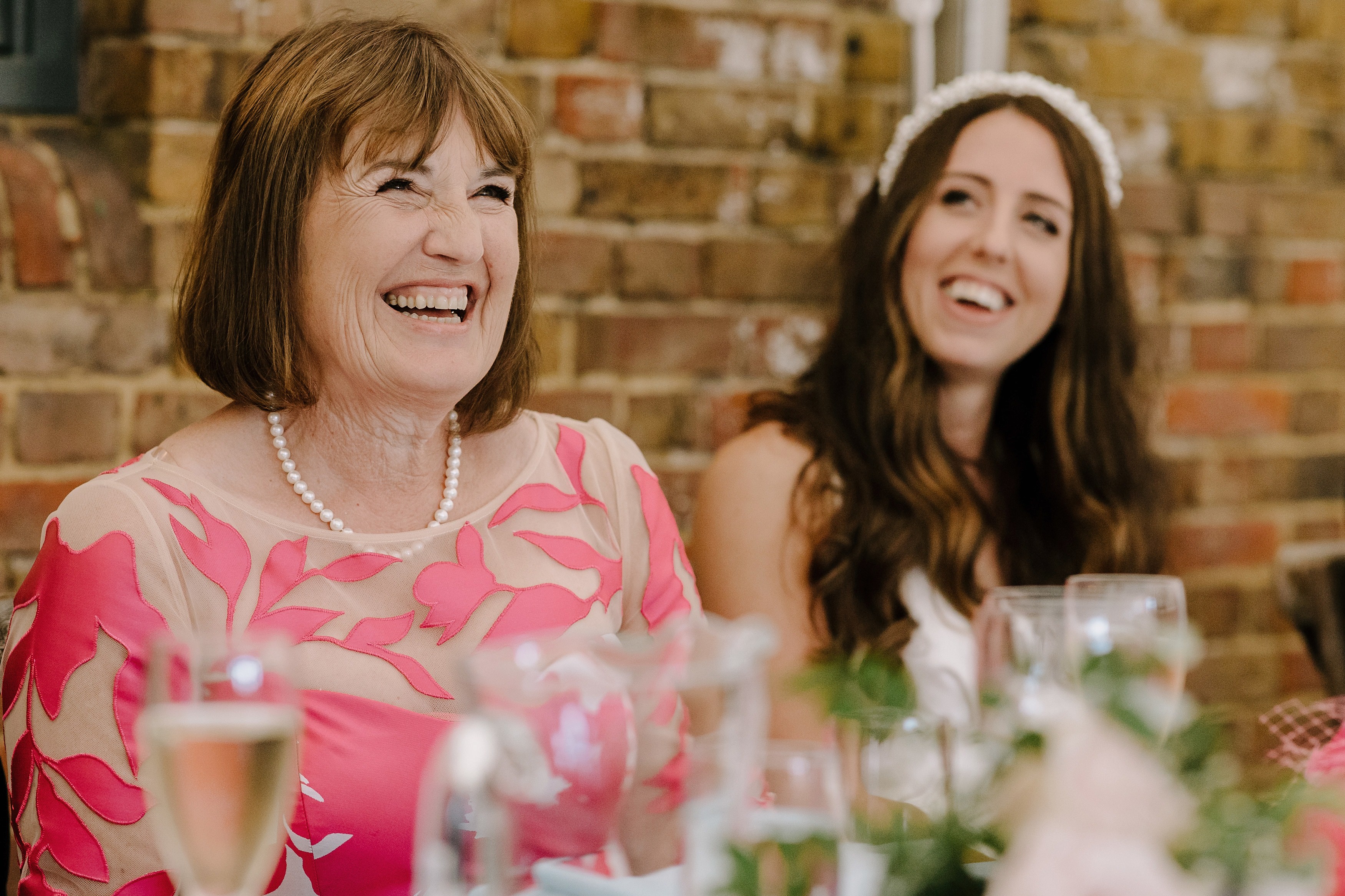 Bride and mother of the bride laughing during a wedding speech