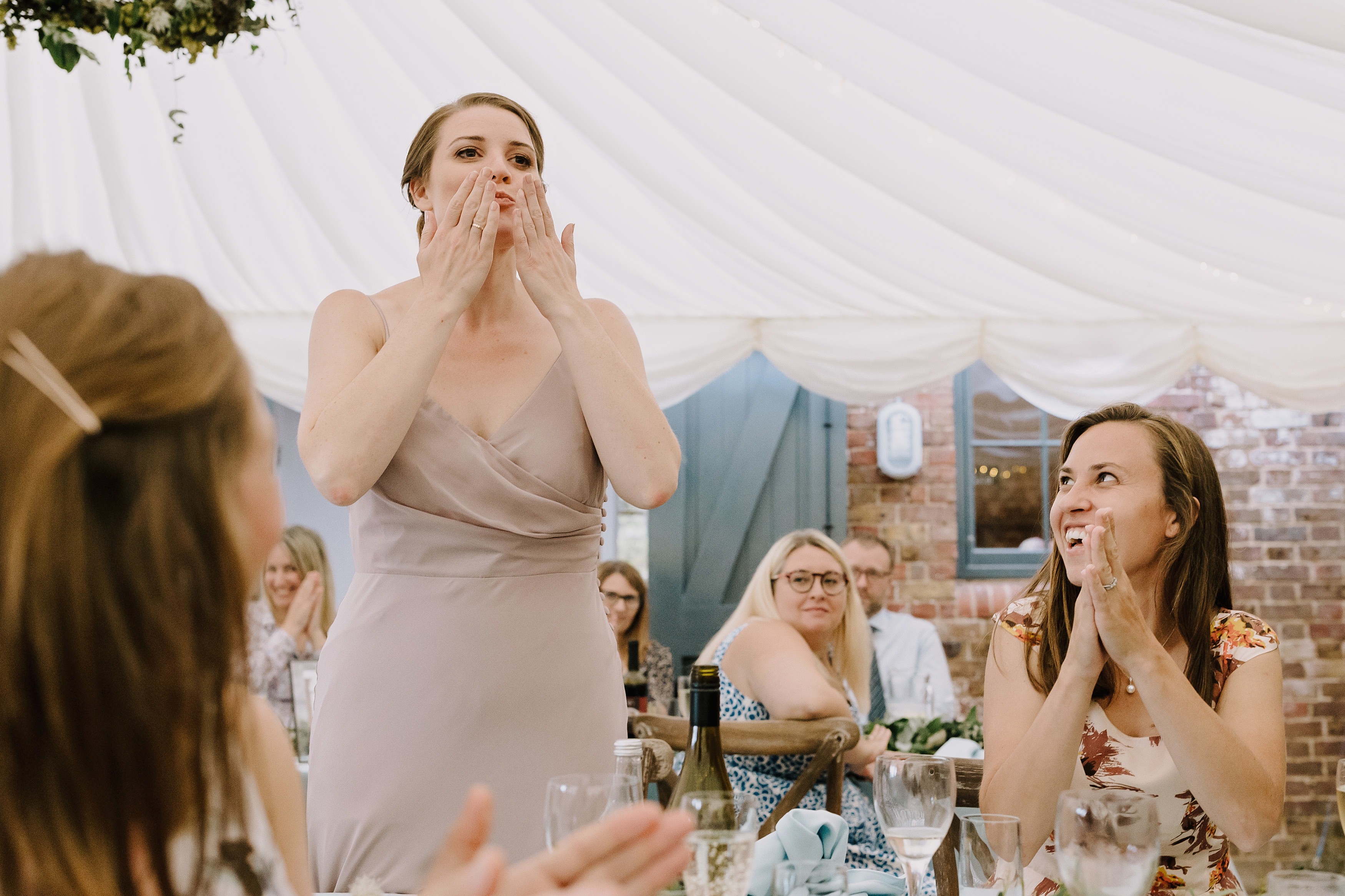 A bridesmaid blowing someone a kiss during their wedding speech