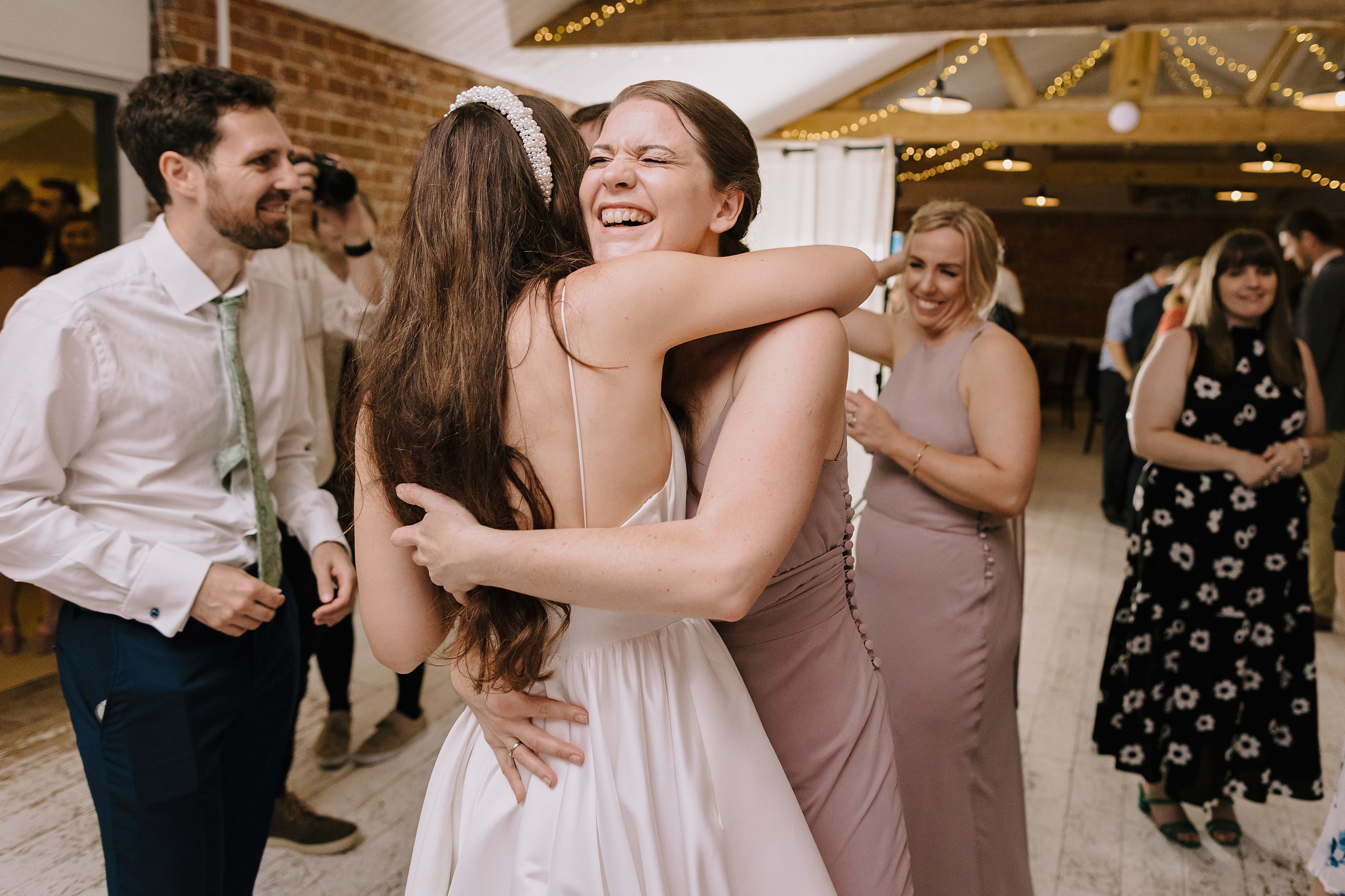 The bride hugging one of her bridesmaids on the dance floor