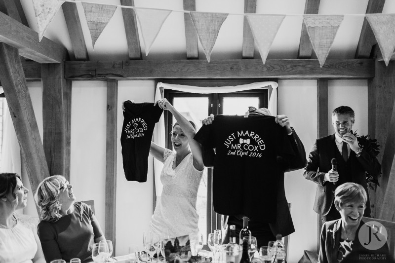 Bride and groom lift up t-shirts they were given as a wedding present