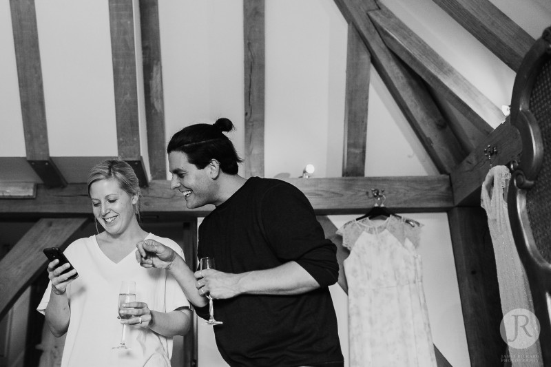 Bride laughing with her friend before the ceremony at the old Kent barn