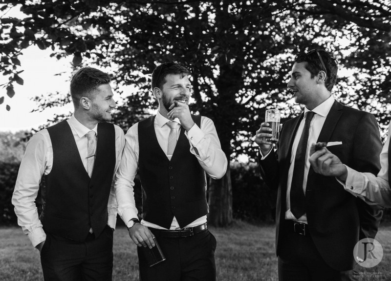 Groomsmen smoking cigars in the Hendall Manor Barns grounds