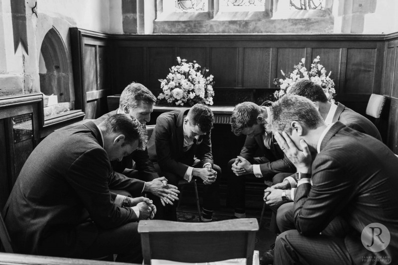 Groom praying with his groomsmen before the ceremony